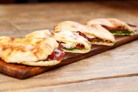 Sliced pizza calzone whith ham on wooden board on wooden table.