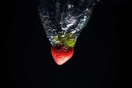 A strawberry splashing into waterの写真素材