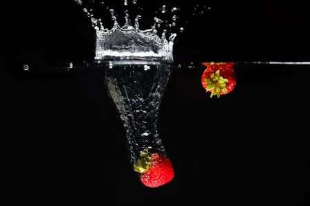 Two strawberrys splashing into waterの写真素材