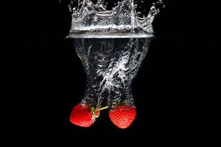 Two strawberrys splashing into waterの写真素材