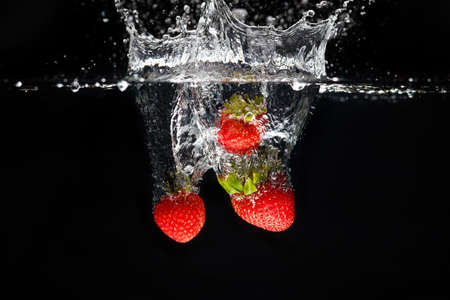 Three strawberrys splashing into waterの写真素材