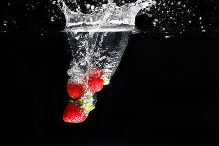 Three strawberrys splashing into waterの写真素材