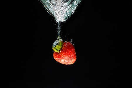 A strawberry splashing into waterの写真素材