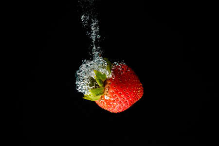 A strawberry splashing into waterの写真素材