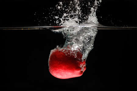 A apple falls deeply under water with a big splash.の写真素材