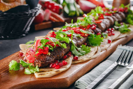 Lula Kebab on the wooden service plank with garnet and arabic breadの写真素材