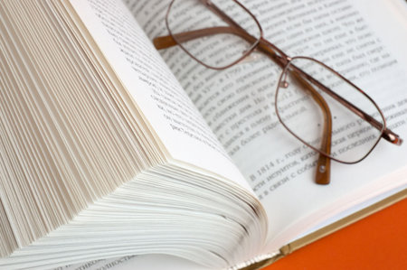 opened book and glasses on dark red backgroundの写真素材