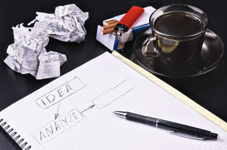 Notebook a pencil the crumpled sheets of a cigarette of coffee against a dark backgroundの写真素材