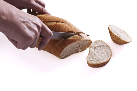 Cutting of a grain long loaf on a light background