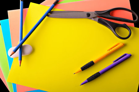 Scissors, pencils and pens on a yellow cardboard