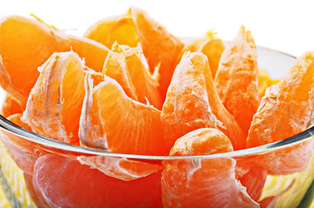 slices of fresh mandarin group in a glass container located on a white backgroundの写真素材