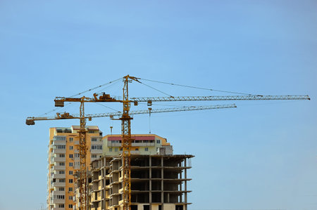 Tower cranes on the construction of a residential building on a background of blue sky
