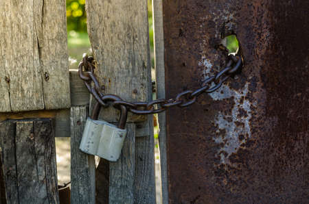 old padlock with chain on wooden gateの写真素材