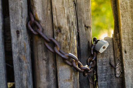 old padlock with chain on wooden gateの写真素材