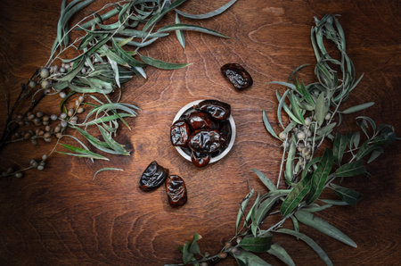 autumn background with date fruits and branches on dark wooden background
