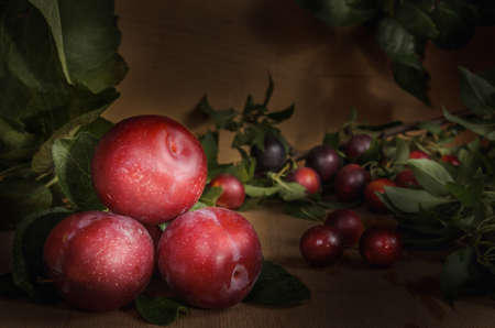 ripe juicy plum fruits on a dark wooden background in bulkの写真素材