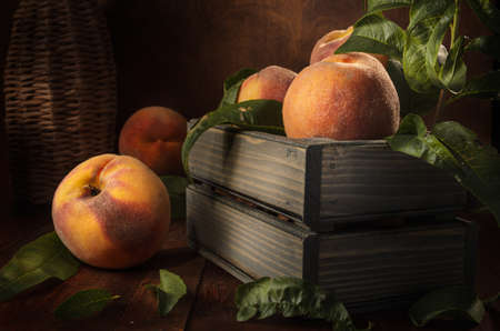 peaches in a wooden box on a dark wooden background in a rustic styleの写真素材