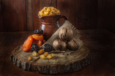 ceramic jug, dried apricots and other dried fruits on a dark wooden backgroundの写真素材