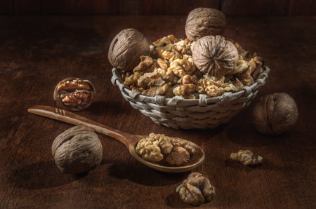walnuts and kernels in a basket on a dark wooden background