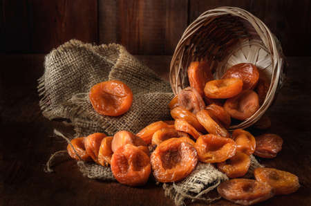 dried apricots in a basket on a dark wooden backgroundの写真素材