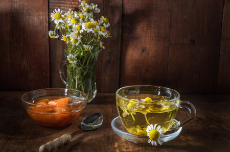herbal tea cup and daisy medicinal herbs bunches on wooden boardの写真素材