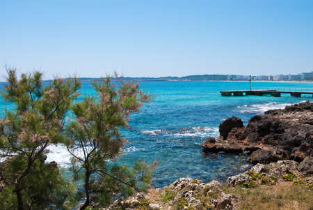 Rocky coast of Cala Bona and sunlit Mediterranean Sea under solid blue sky, Majorca island, Spainの写真素材
