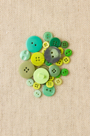 Many green sewing or clothing buttons on hessian
