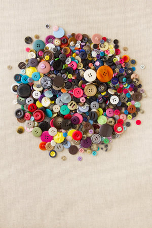 Pile of mixed buttons, dark and bright, on hessian