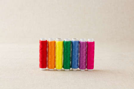 Spools or bobbins of thread, brightly coloured, arranged in rainbow colour formationの写真素材