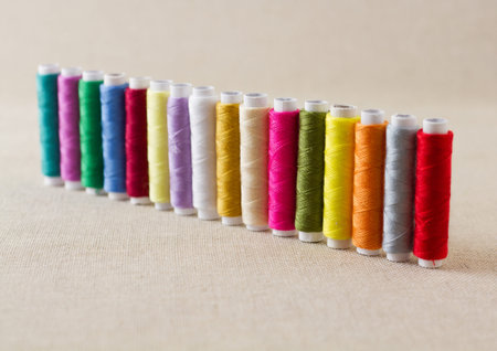 Spools and bobbins of thread, brightly coloured, arranged in a row