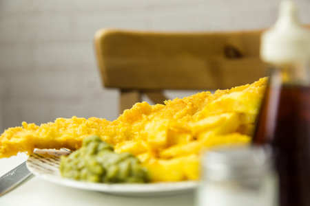 Traditional British takeaway meal of fish and chips with mushy peas on a newsprint plateの写真素材