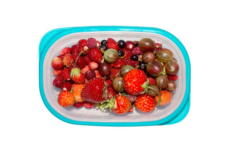 Wild berry. Berries in a plastic container on a white background. Assorted berries.