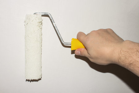 Painting walls with a roller of white paint.