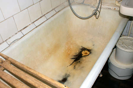 An old cast-iron rusty bathtub.Cast iron bathtub background.Drain in the bathroom with rust.の写真素材