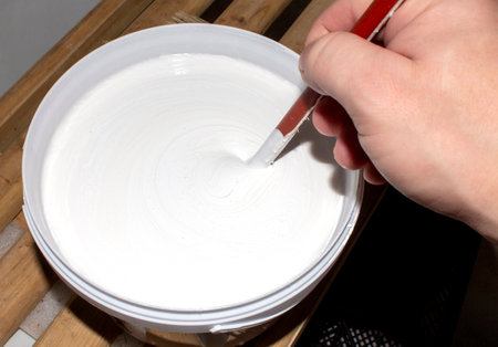 Acrylic white matte paint in a jar.Stir in the acrylic paint.Acrylic paint background.Paint preparation.の写真素材