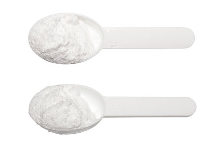 Creatine in a measuring plastic spoon on a white background.Creatine monohydrate.Creatine for endurance in training.Creatine powder background.の写真素材