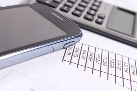 Financial charts on the table with phone and calculator