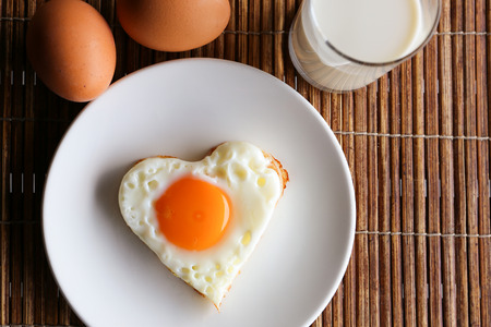 Fried egg in heart shape and milkの写真素材