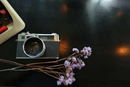 Color film camera and  vintage antique typewriter with purple dry flowers on the black metal table - Top view with copy spaceの写真素材