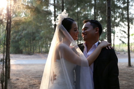 Asian couple in lovely wedding dresses in a pine forestの写真素材