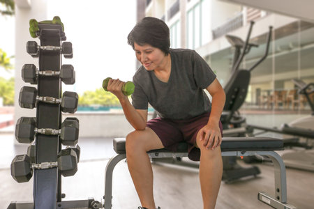 Happy Asian woman work out in gym on weight