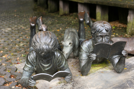 Metal sculpture of boy and girl lie down on the floor and read bookの写真素材