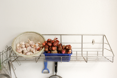 Fresh garlic and red shallot in basket in kitchenの写真素材