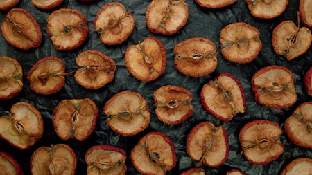Beautifully arranged dried apple slices displayed attractively on a dark backgroundの写真素材
