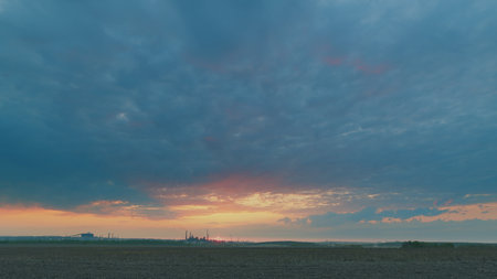 A Stunning Sunrise Displaying Vibrant Colors Over a Field Beneath a Dramatic Cloudy Skyの写真素材