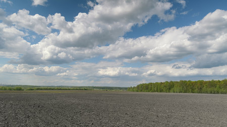 A scenic landscape featuring a beautiful cloudy sky above a freshly plowed fieldの写真素材