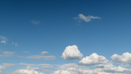 A gorgeous scenic view of the bright blue sky adorned with soft and fluffy clouds aboveの写真素材
