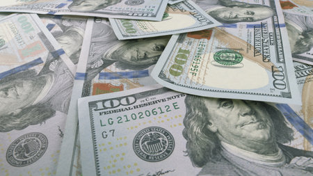 Scattered US Dollar Bills Resting on a Table Surface for Examination and Analysisの写真素材