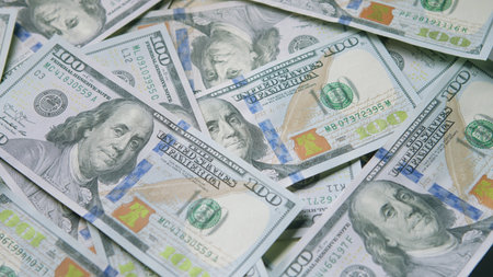 A closeup view of numerous U.S. Hundred Dollar Bills stacked together in a pile