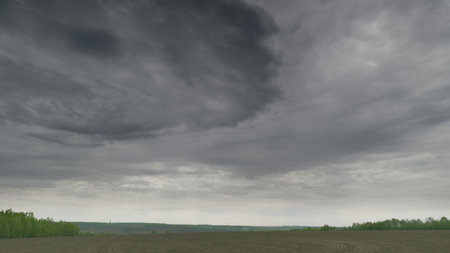 A Dramatic and Cloudy Sky Sprawls Over a Vast and Barren Field Stretching to the Horizonの写真素材